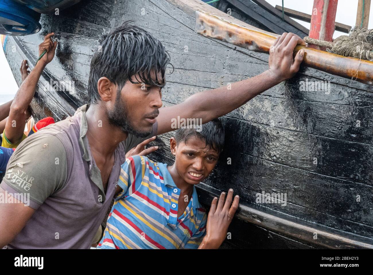 Men Hauling Moon Shaped Fishing Boats in a Fishing Village South of Cox's Bazar Stock Photo