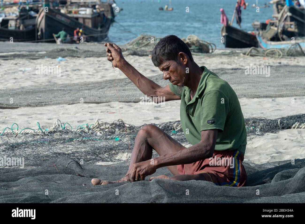 Man Repairing Fishing Net in a Fishing Village North of Cox's Bazar Stock Photo