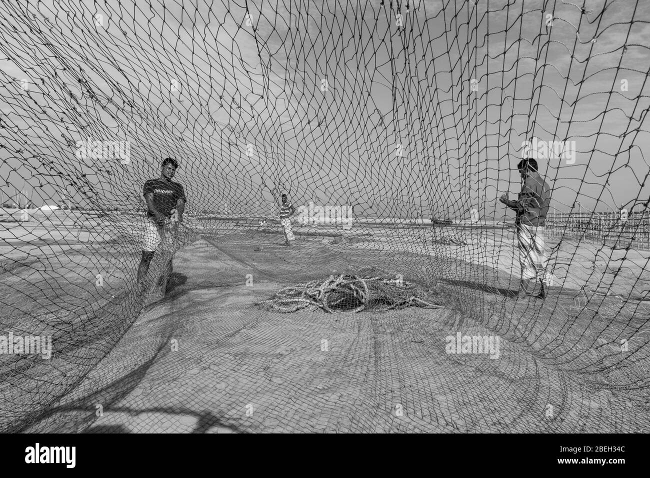 Men Repairing Fishing Net in a Fishing Village North of Cox's Bazar Stock Photo