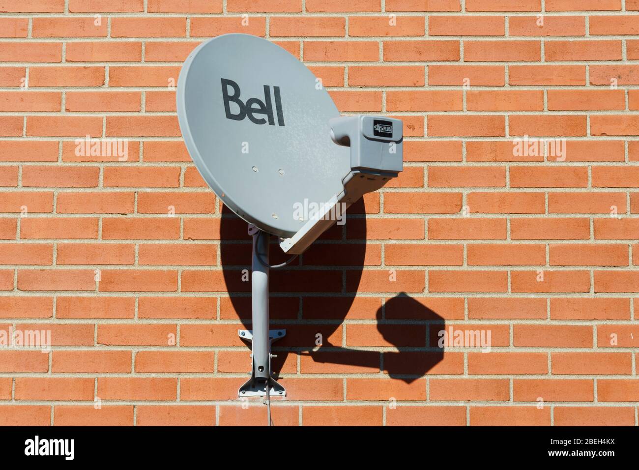 Broadband Bell satellite dish on a red brick wall. Stock Photo