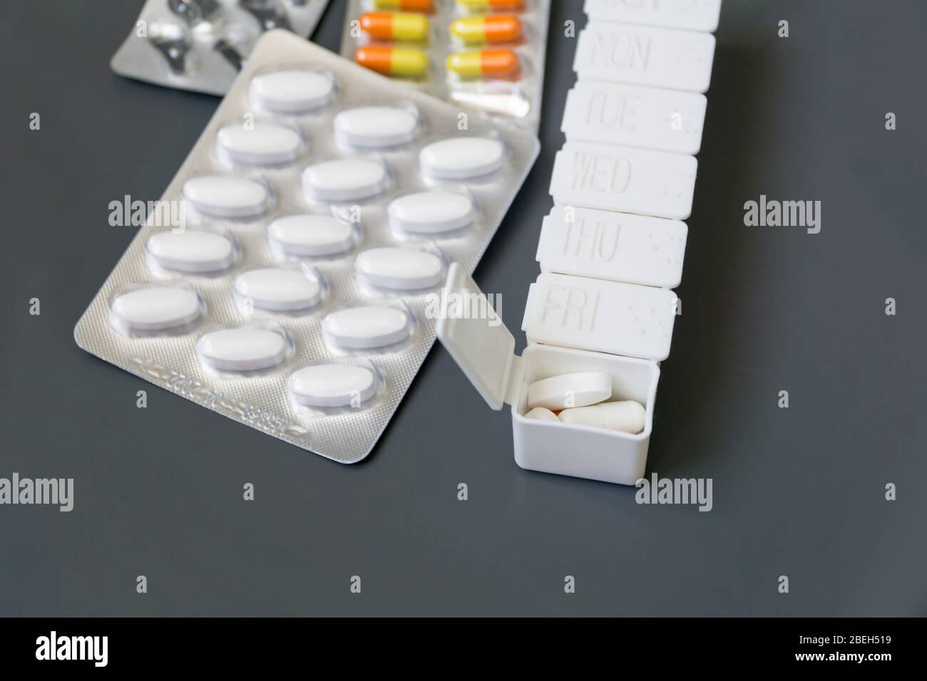 Medicine pills, tablets and capsules different colors in pill box on grey background, selective focus. Health care. Stock Photo