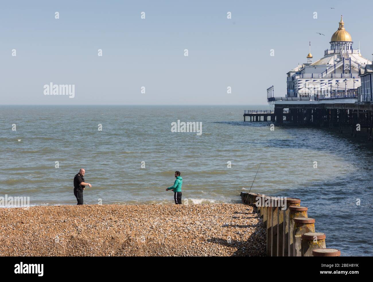 COVID-19. A policeman talks with an angler by Eastbourne pier Stock Photo
