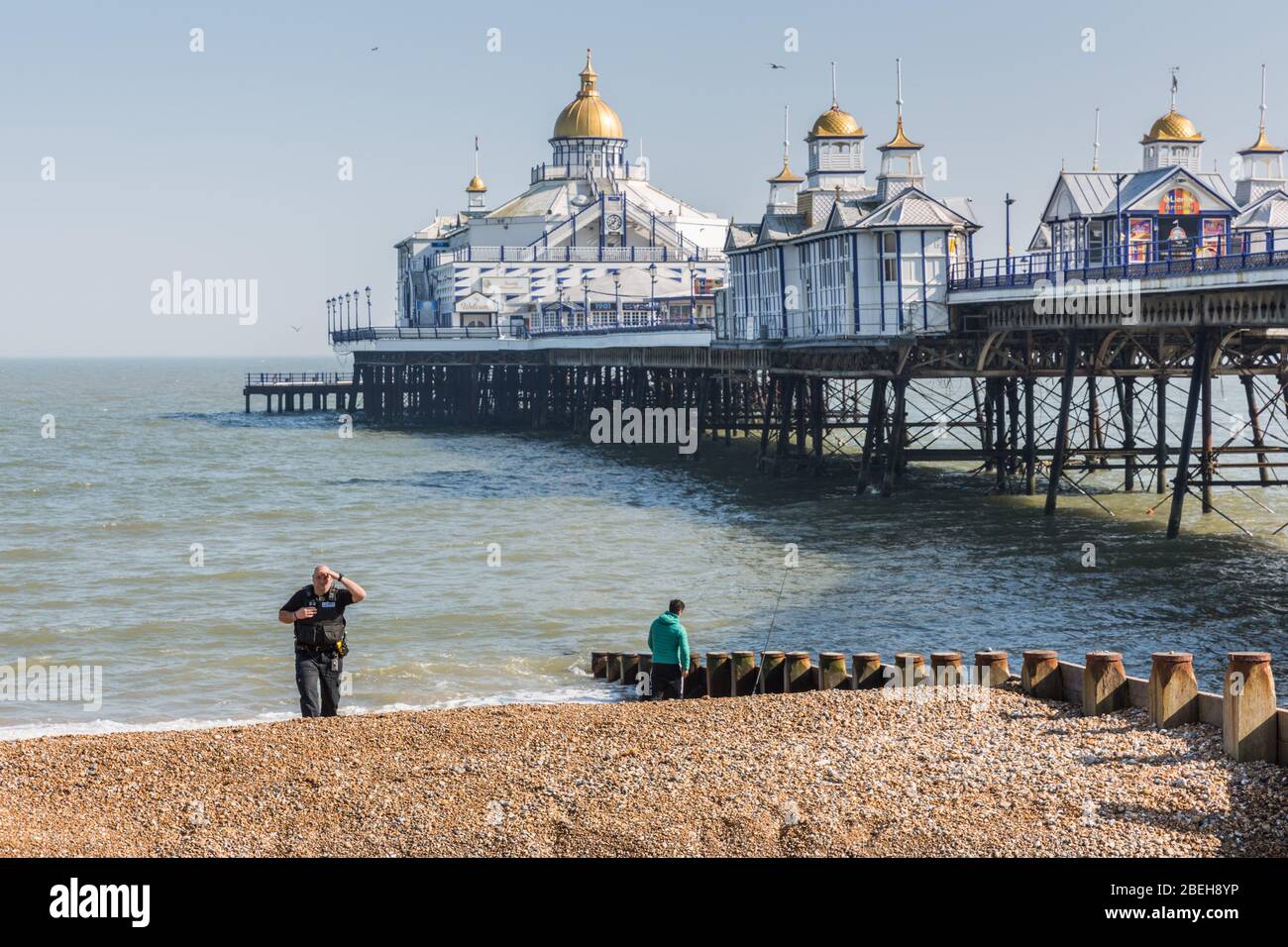 COVID-19. A policeman talks with an angler by Eastbourne pier Stock Photo