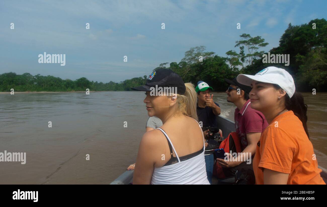 Group of tourists sailing in a wooden boat on the Aguarico river on a sunny morning Stock Photo