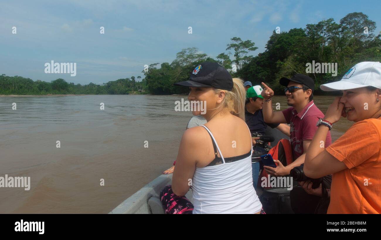Group of tourists sailing in a wooden boat on the Aguarico river on a sunny morning Stock Photo
