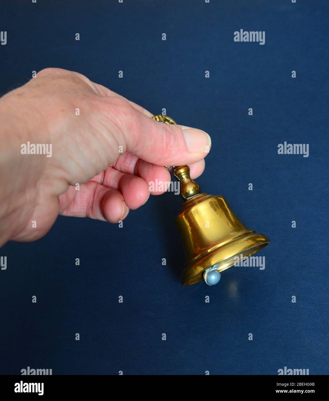 Hand ringing a brass handbell. Stock Photo