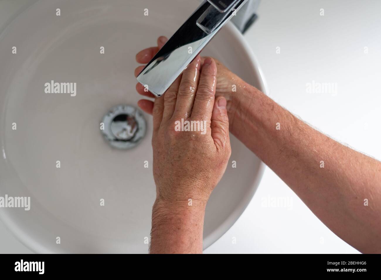 Man with wrinkly hands washes his hands during the Covid-19 outbreak ...
