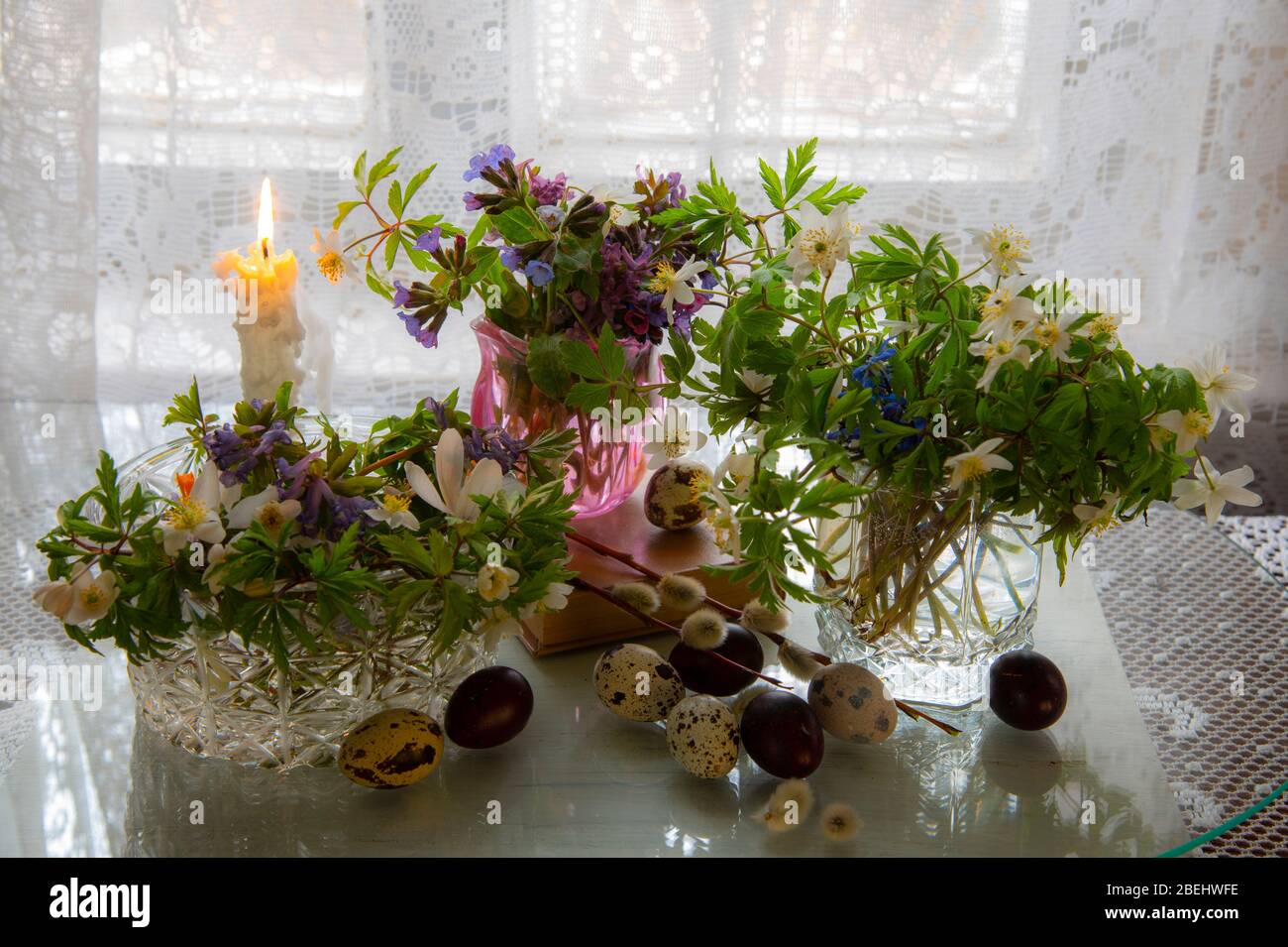 Several vases with spring flowers and Easter eggs on a light background.  Stock Photo