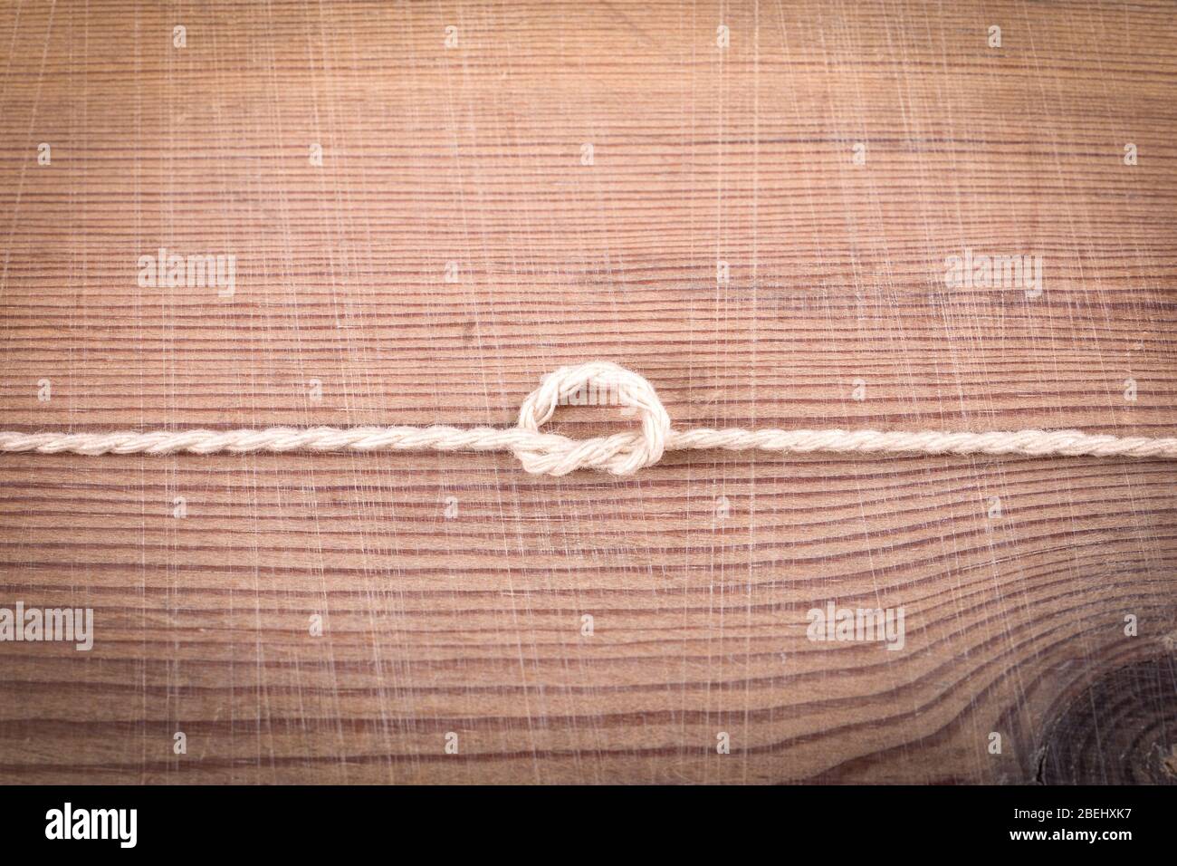 Overhand Knot. Example of training and information. White cord on a wooden background Stock Photo
