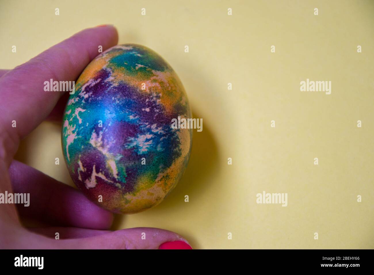 Human hand holding single colorful egg, body part, fingers, one multicolored egg, Easter