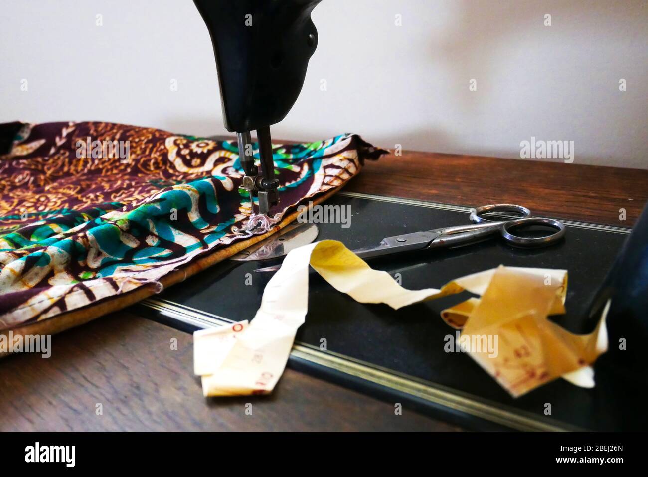 Close-up of vintage sewing machine with fabric, scissors and measuring tape Stock Photo