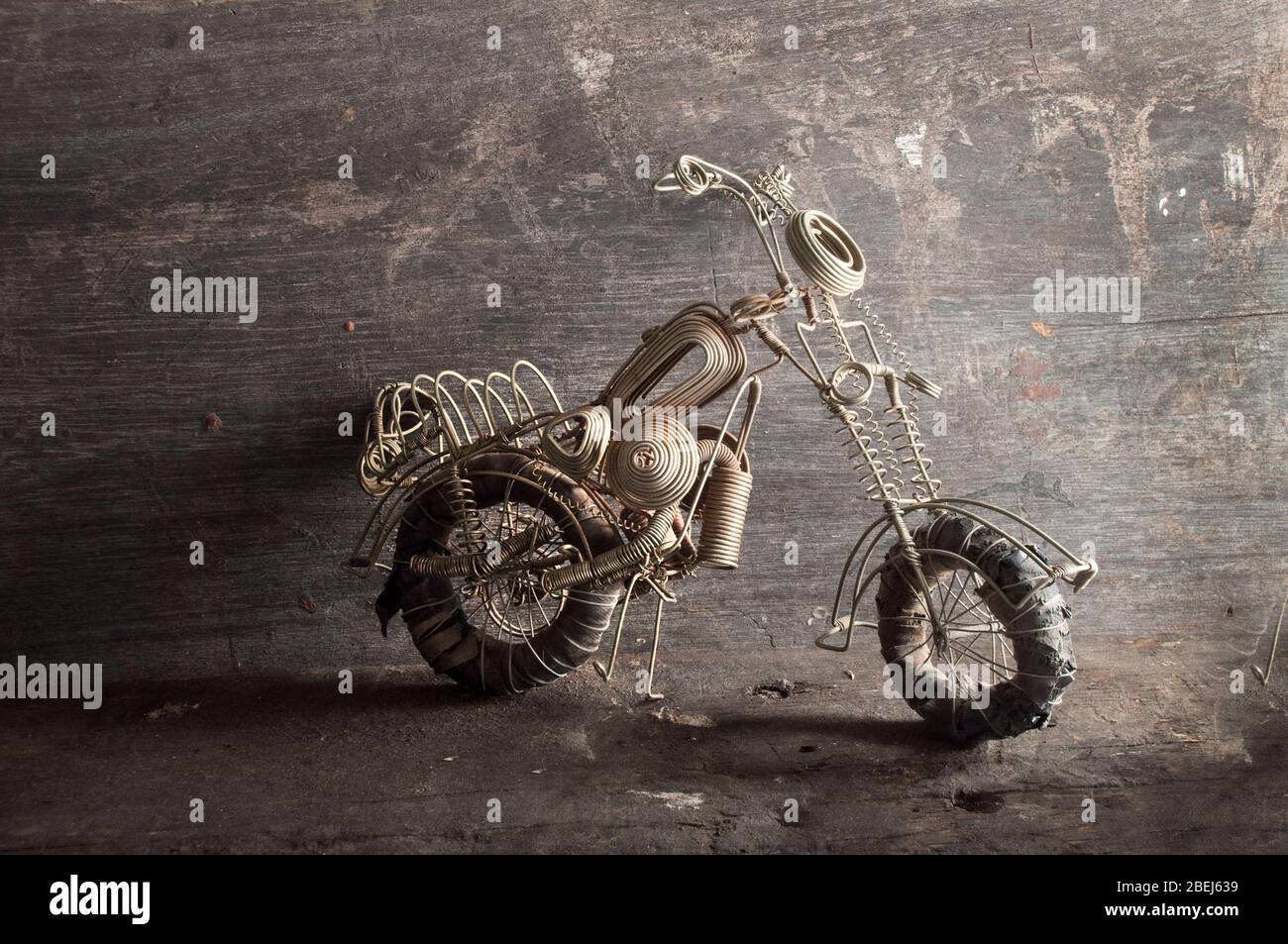 Hand made wire model of a motor cycle from Malawi about 1989. About 35cms long Note rubber tires Studio shot on old dark wood background. Stock Photo