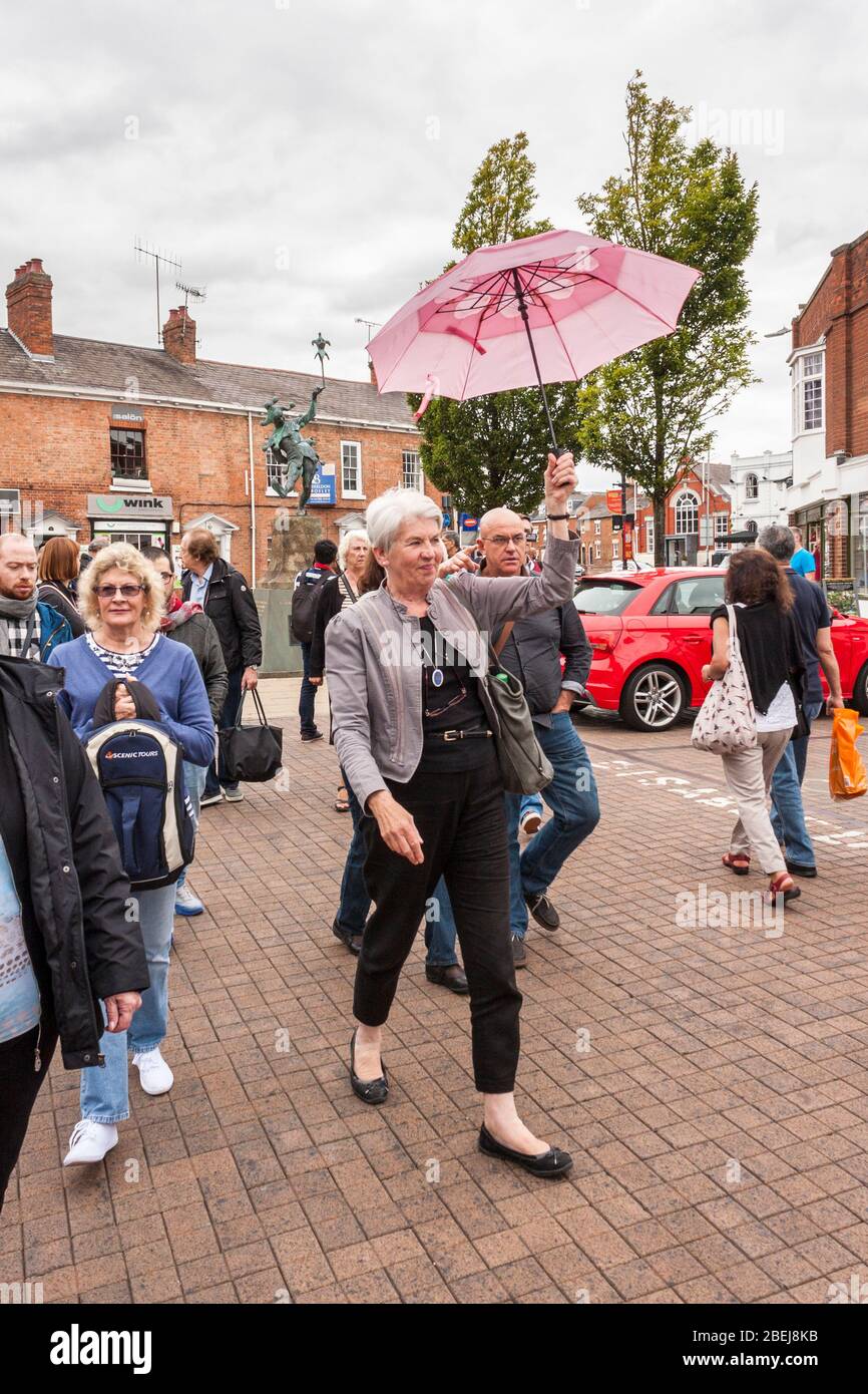 Tour guide leads tourists around visitor attractions in Stratford-upo-Avon, Warwickshire, England, GB, UK Stock Photo