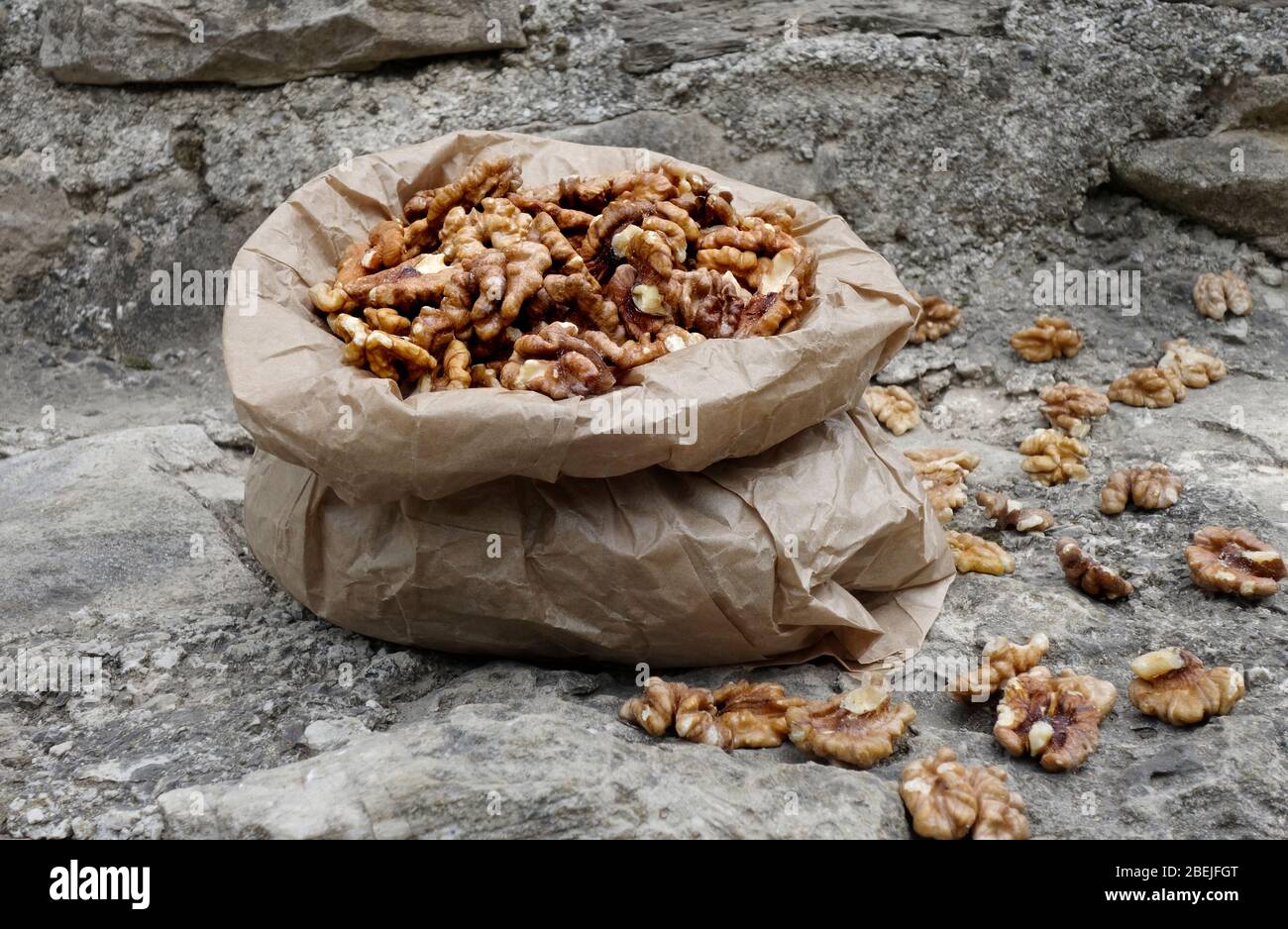 Walnut kernels in paper bag on stone background Stock Photo