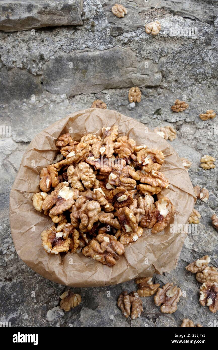 Walnut kernels in paper bag on stone background Stock Photo