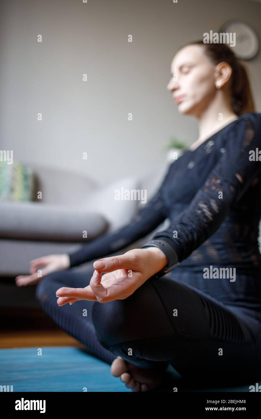 Young woman practicing yoga meditation at home quarantine. CLose up focusing Stock Photo