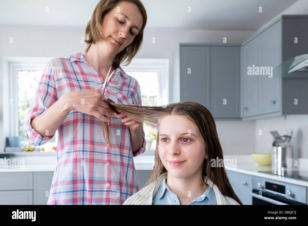 Mother Cutting Teenage Daughters Hair At Home During Lockdown Stock Photo