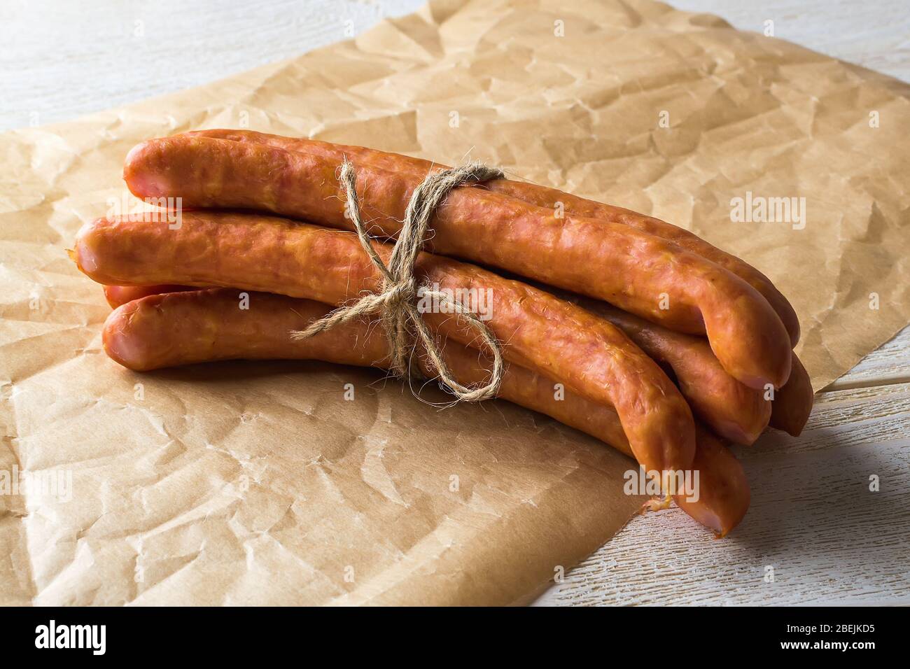 Bunch of thin smoked sausages on a brown parchment wrapping paper