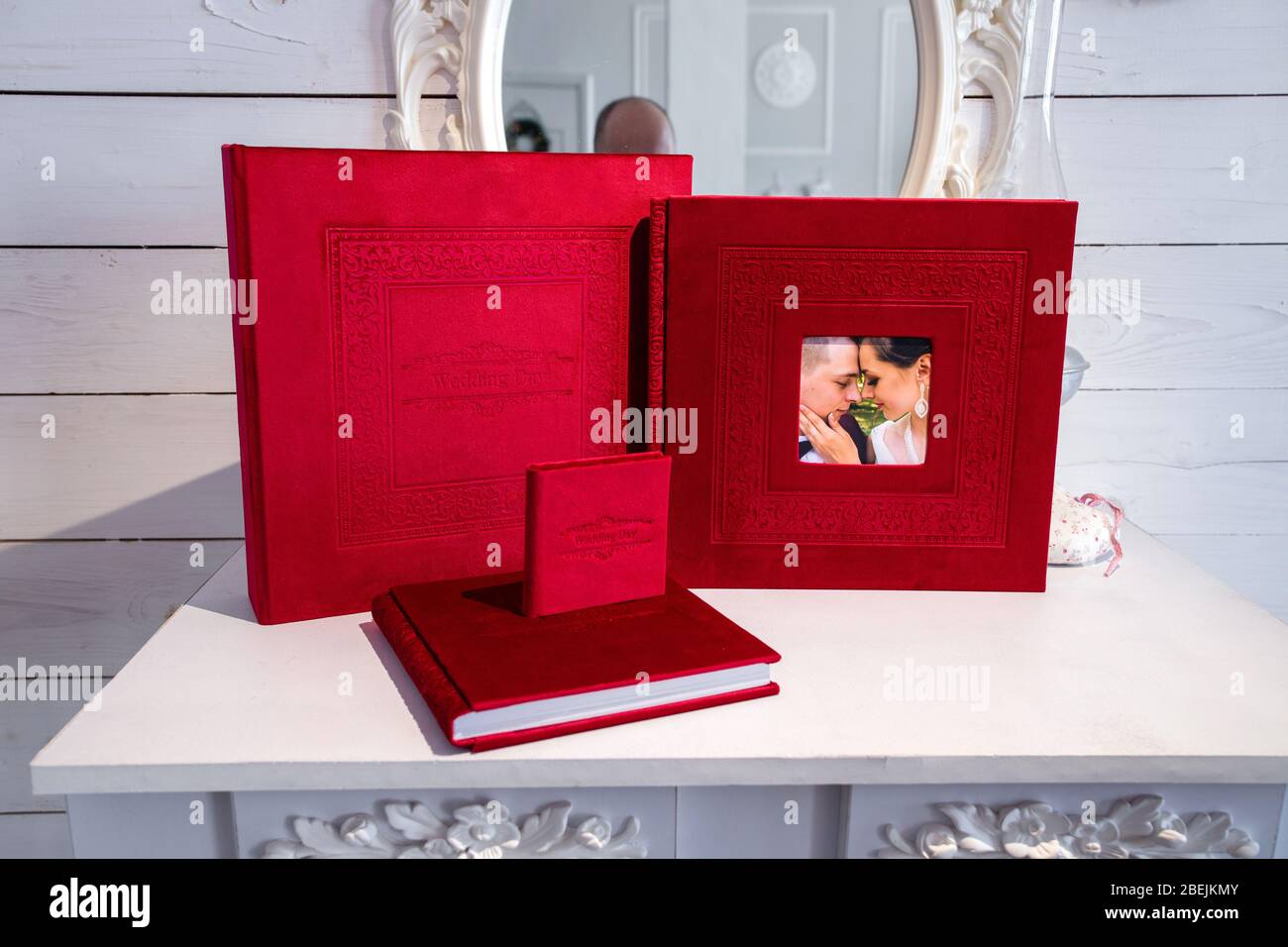 Photo album with a box on a wooden background. Photo book with embossing. photobook with a gift box Photo album with a hard cover Bright red photoalbu Stock Photo