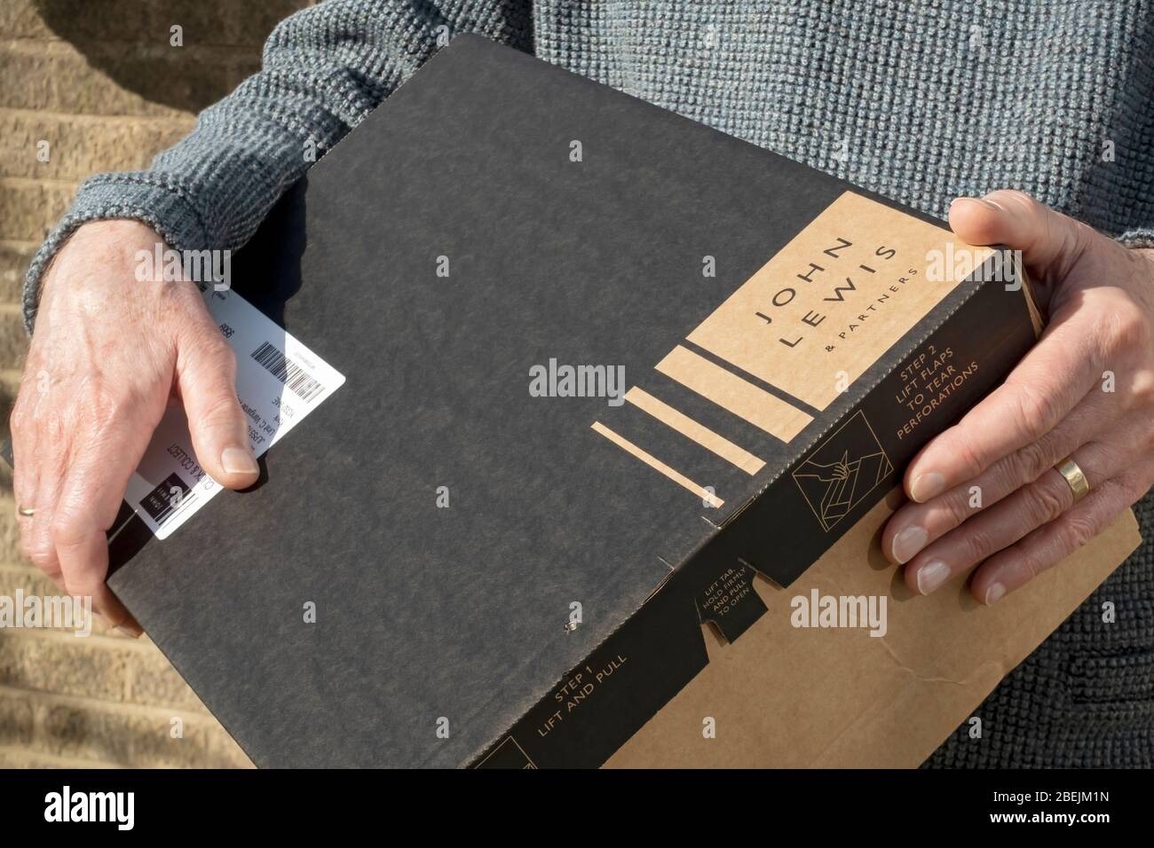 Close up of person man carrying holding John Lewis box click and collect online delivery parcel package England UK United Kingdom GB Great Britain Stock Photo