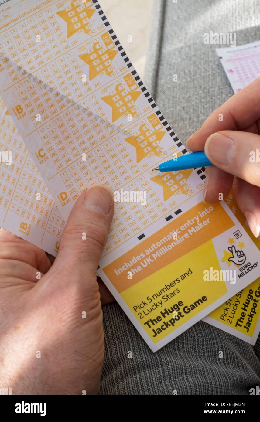 Close up of person man holding filling in EuroMillions Lotto lottery slip form England UK United Kingdom GB Great Britain Stock Photo