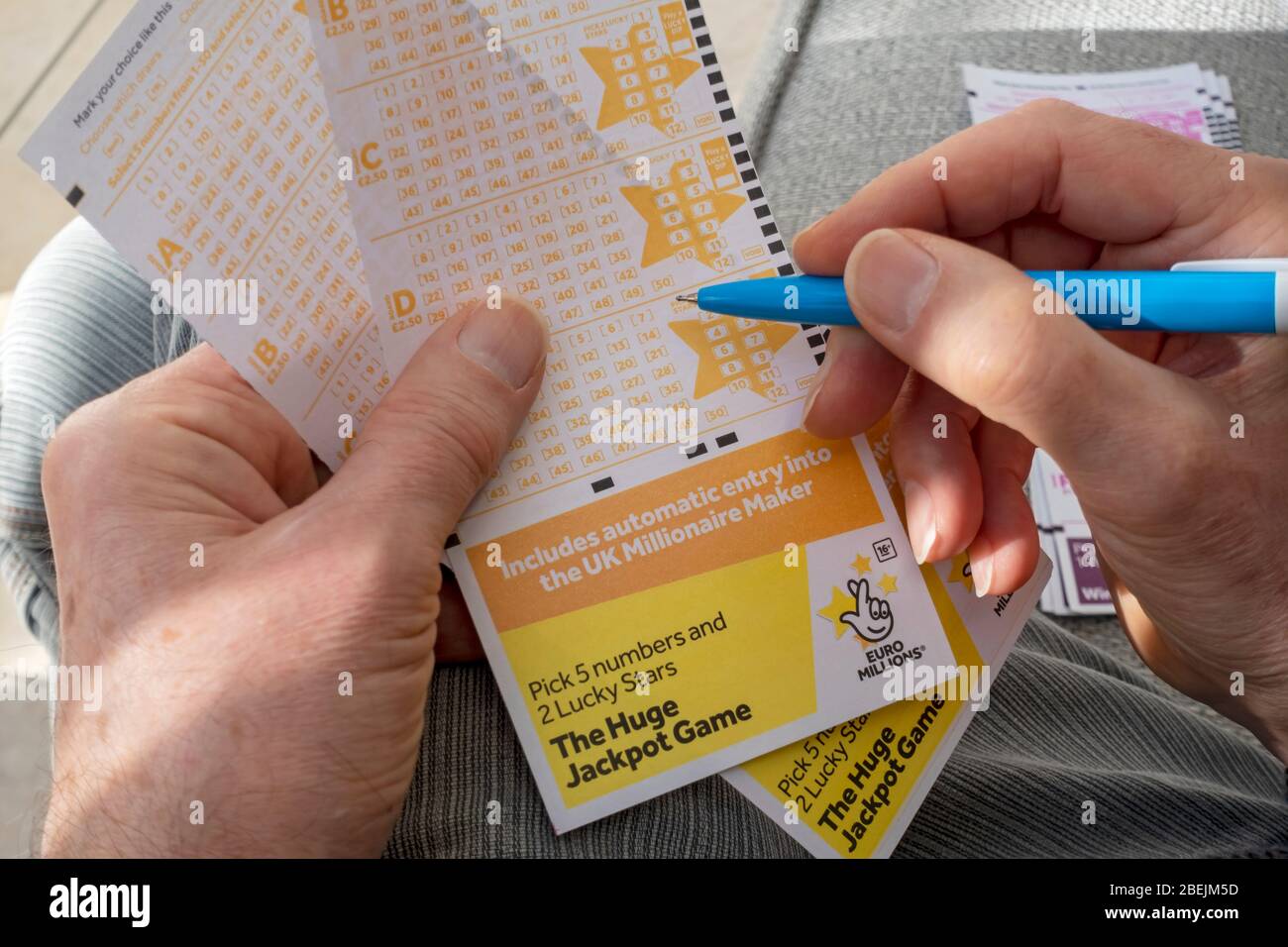 Close up of person man holding filling in EuroMillions jackpot game Lotto lottery slip ticket form England UK United Kingdom GB Great Britain Stock Photo