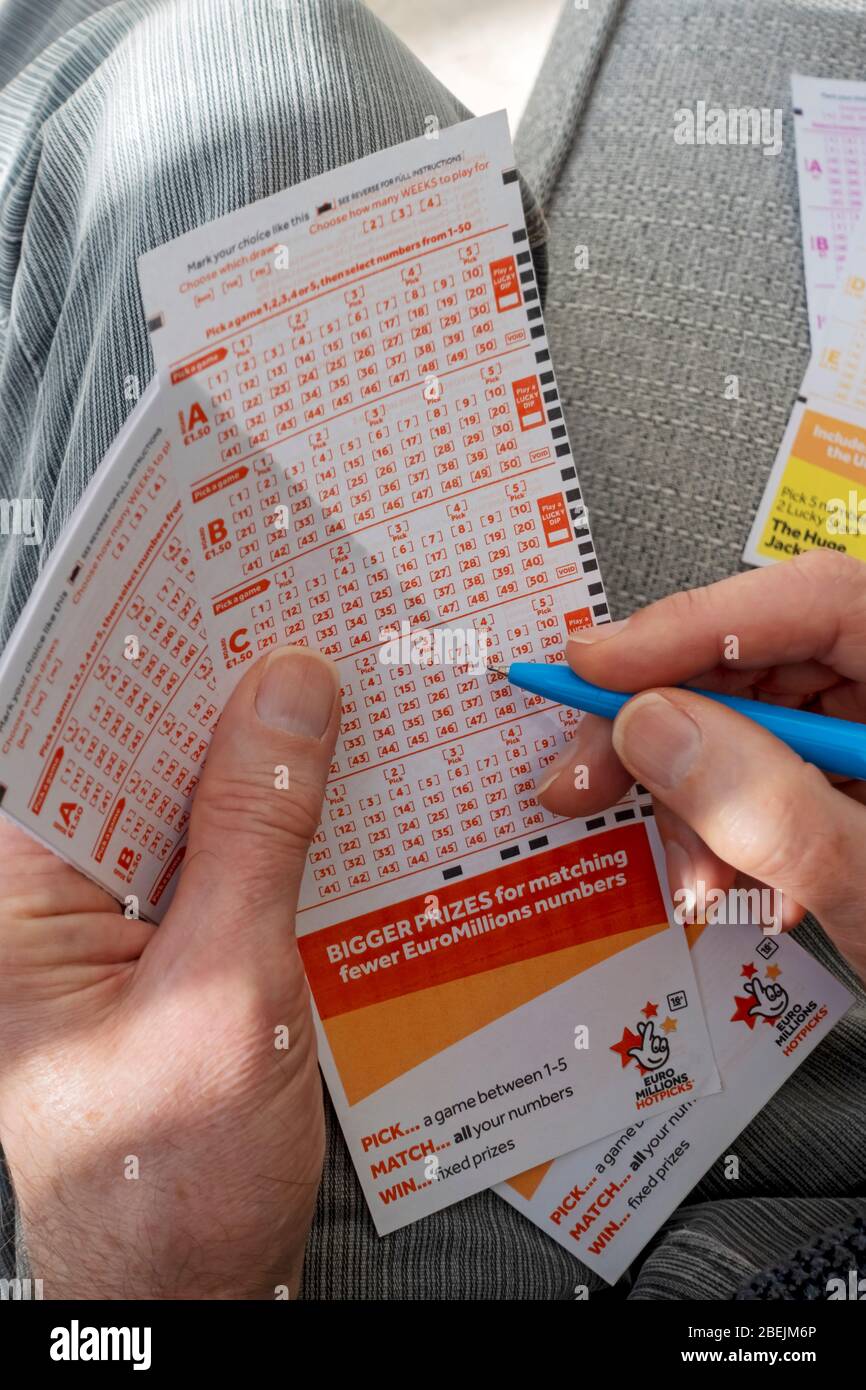 Close up of person man holding filling in EuroMillions Lotto lottery slip form England UK United Kingdom GB Great Britain Stock Photo