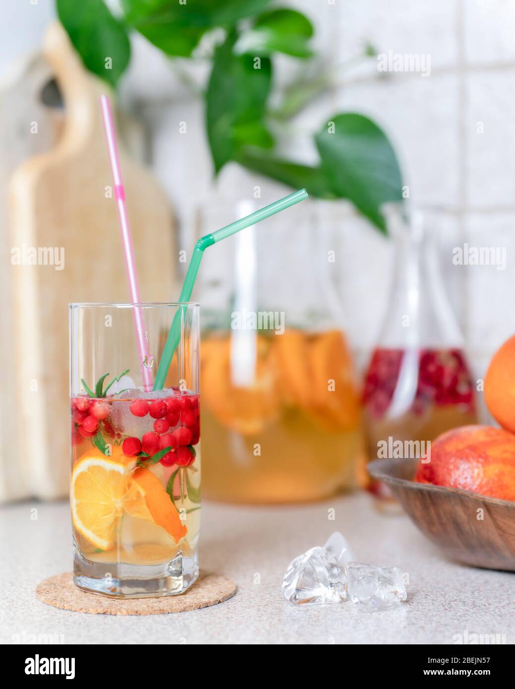 Homemade lemonade with lemon, orange and cranberry with ice in glass and jug on table. Summer cold refreshing drink. Stock Photo