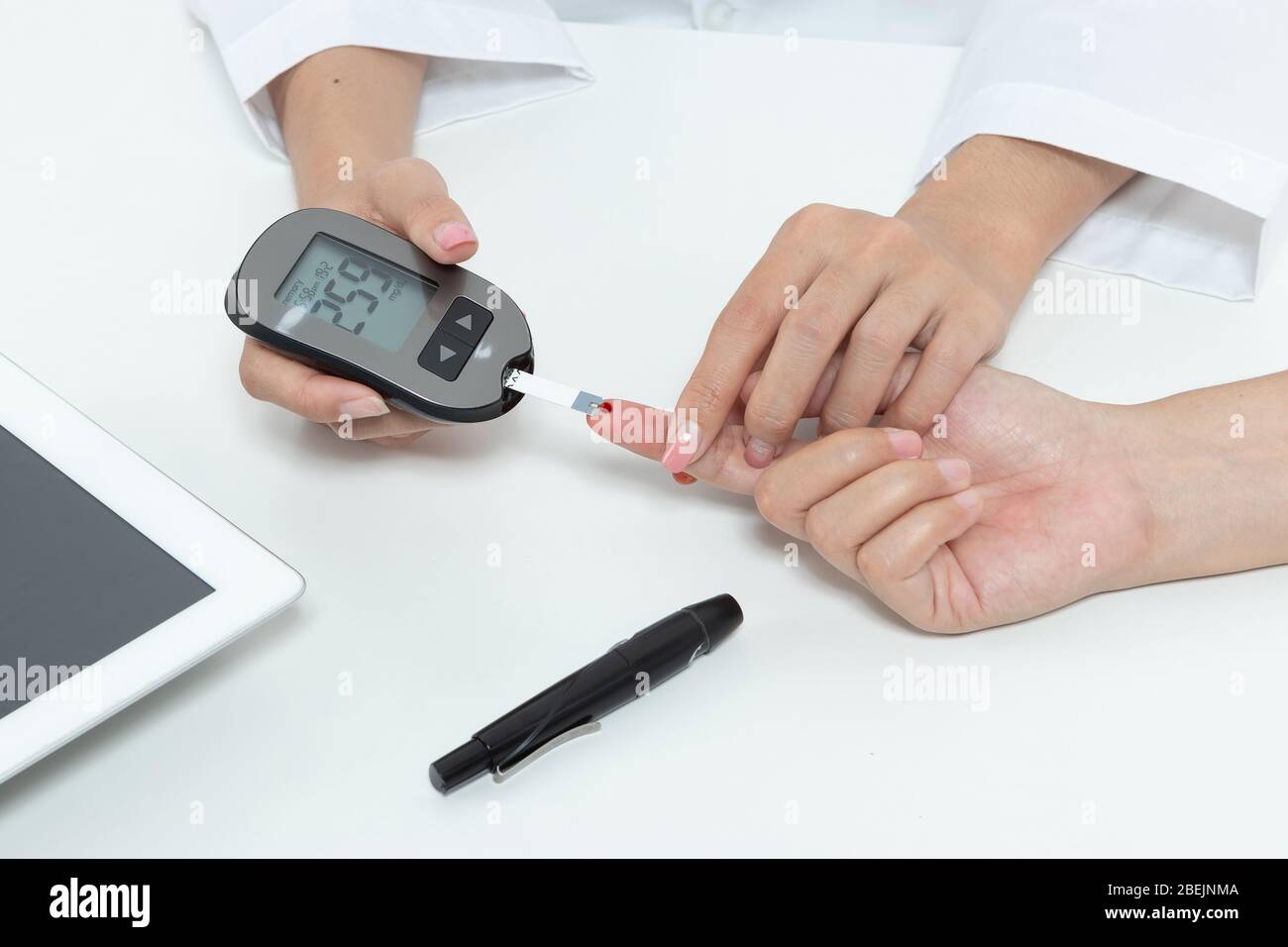 check diabetes. patient with diabetes let doctor put a drop of blood on a test strip into a meter for check blood sugar (glucose) levels results. heal Stock Photo