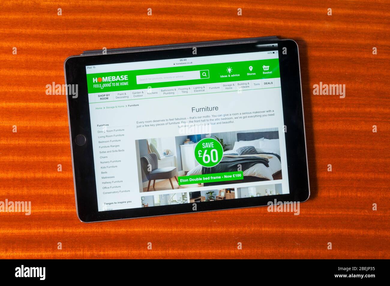 The website of Homebase furniture sellers & DIY store displayed on an iPad tablet computer against a polished wood background. Stock Photo