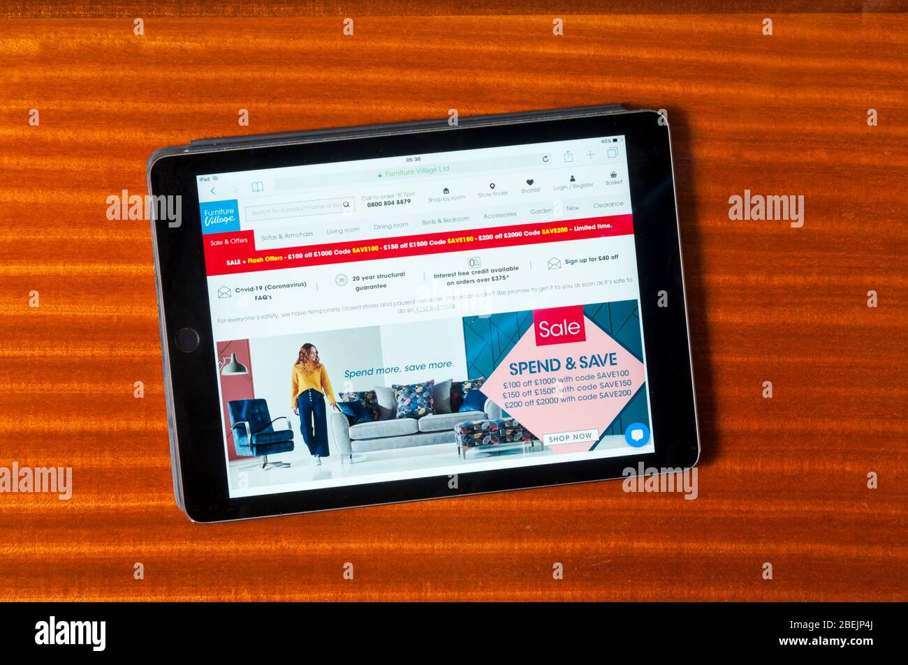 The website of Furniture Village furniture sellers displayed on an iPad tablet computer against a polished wood background. Stock Photo