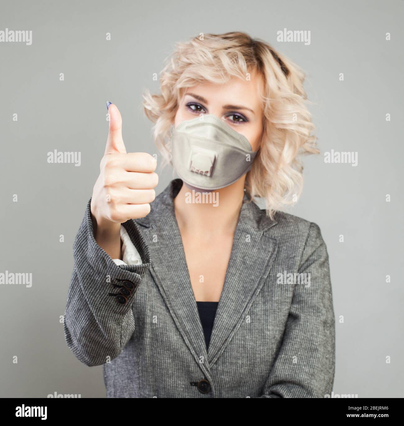 Thumb up. Happy woman in medical mask showing thumb up Stock Photo - Alamy