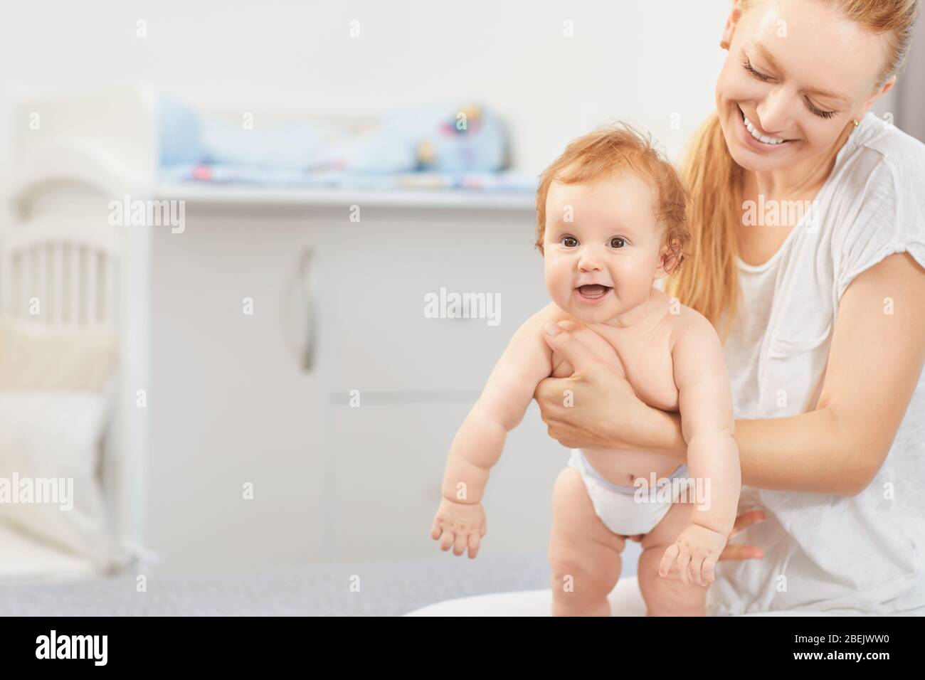 Mother hugging her baby lying on a bed Stock Photo
