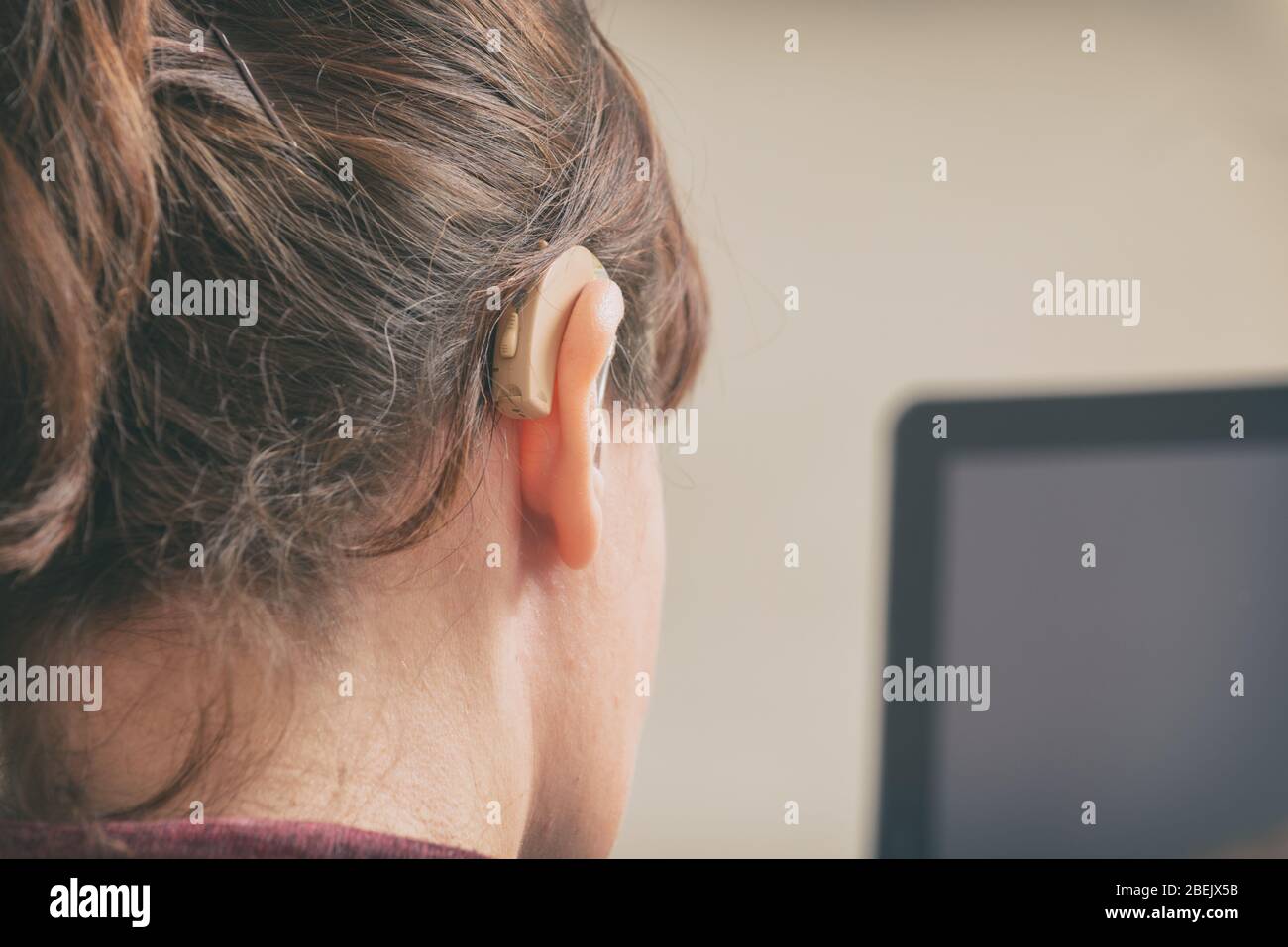 Deaf woman wearing hearing aid and using tablet Stock Photo