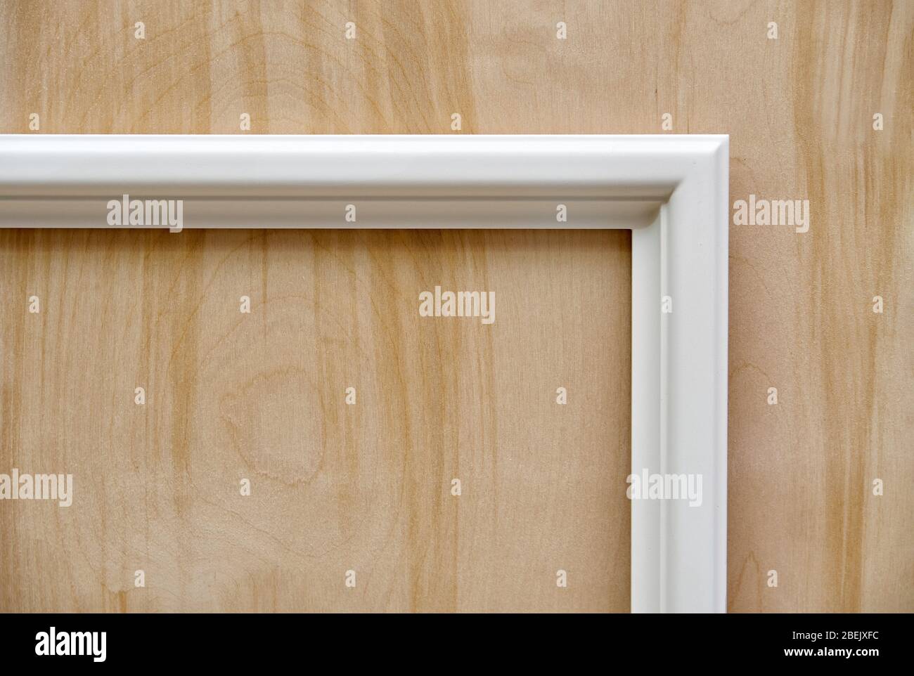 Wooden white molding on plywood background. Wood door manufacturing