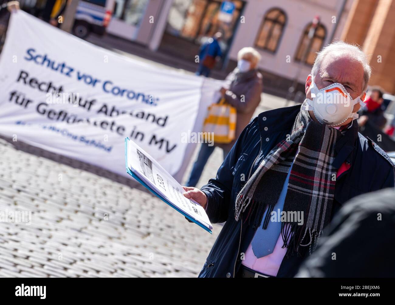 Schwerin, Germany. 14th Apr, 2020. Thomas Lenz, State Secretary in the Ministry of the Interior of the State of Mecklenburg-Western Pomerania, wearing a face mask, accepts the collection of 1,500 signatures from members of the Initiative Pro Bleiberecht (Initiative for the Right of Residence). The petition calls for the right to stay away in accommodations for asylum seekers. The administrative court had previously lifted a ban on assembly. Credit: Jens Büttner/dpa-Zentralbild/dpa/Alamy Live News Stock Photo