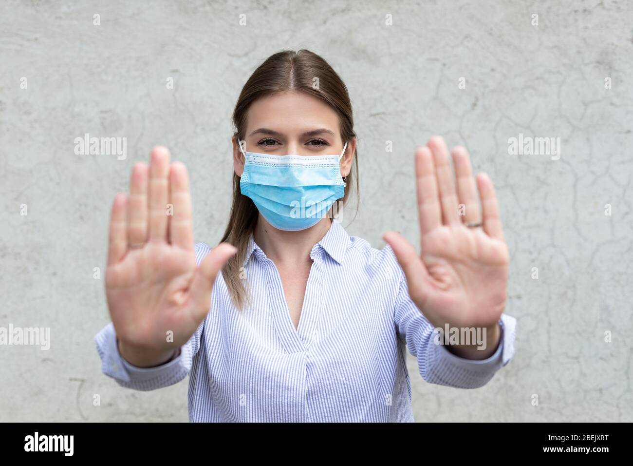 Young caucasian woman wearing surgical mask showing stop sign with ...