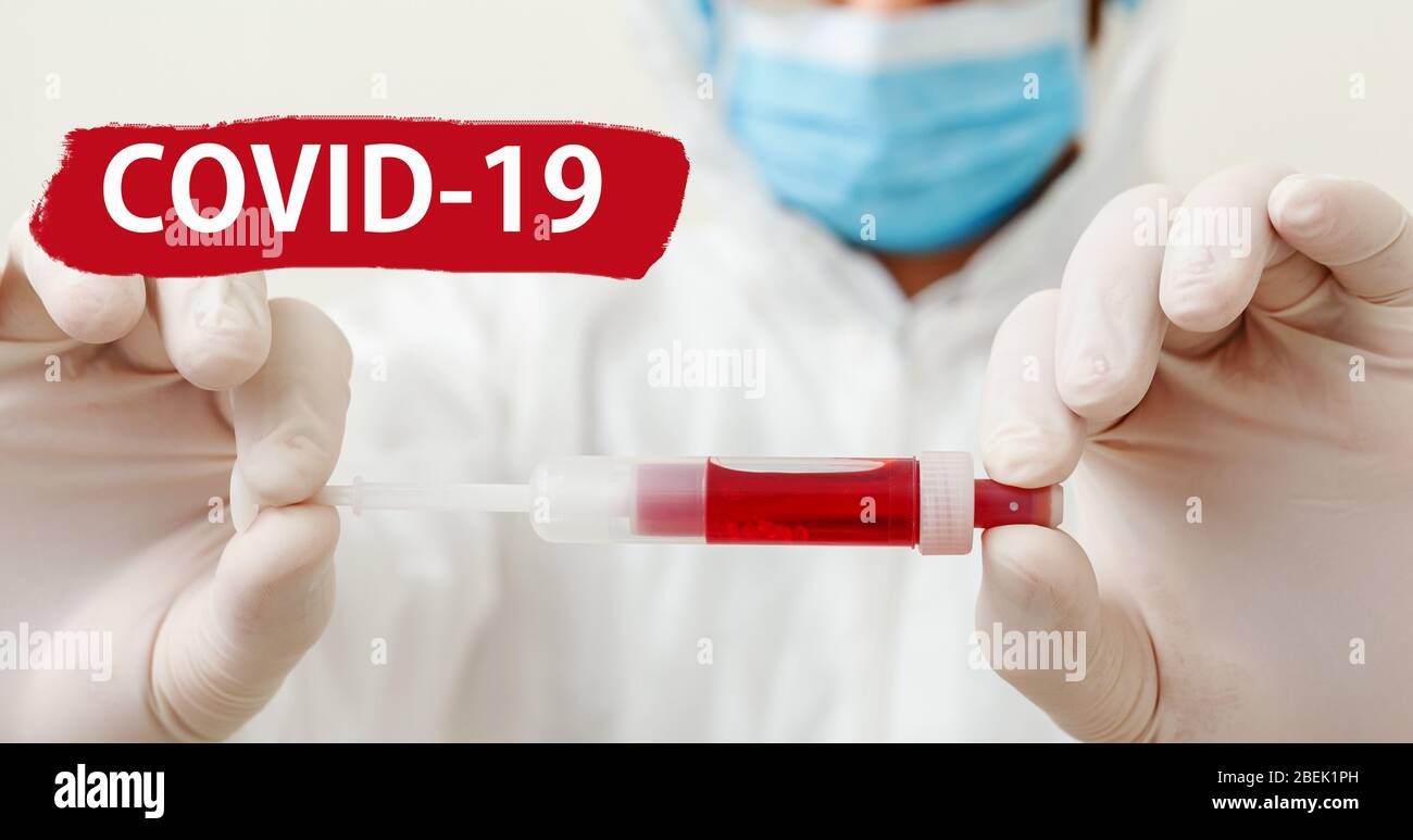 Text covid-19 on red warning sign. Coronavirus blood test in doctors hands. Doctor in mask on white background. Concept of medicine laboratory health Stock Photo