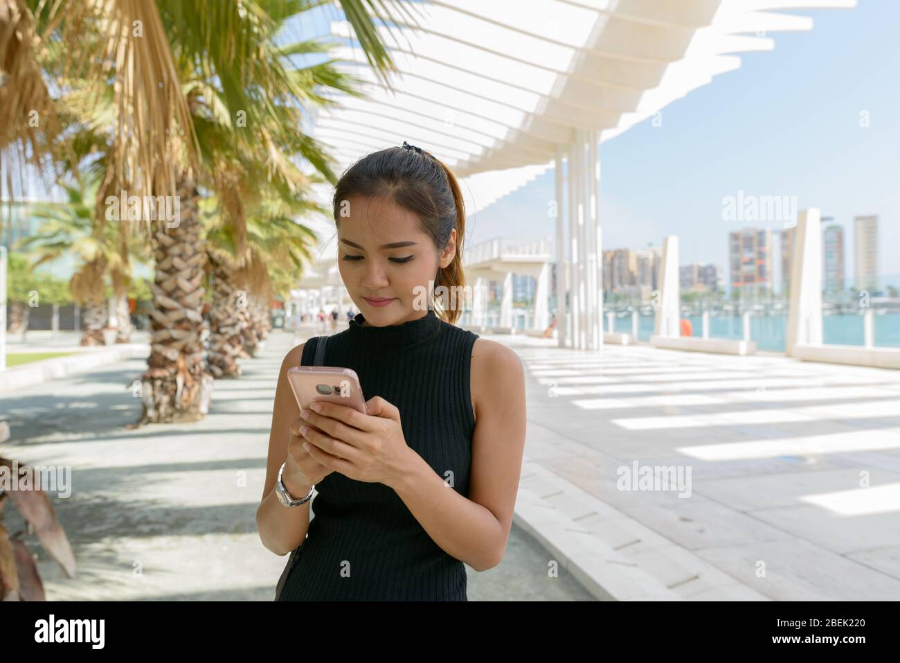 Beautiful woman at Port of Malaga Spain using mobile phone Stock Photo