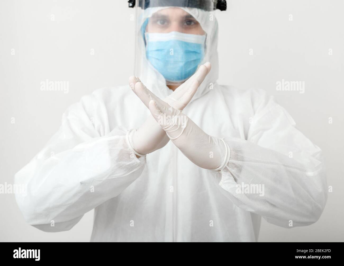 Doctor wearing protection suit and face mask show sign gesture Stop NO pandemic epidemic of Covid-19, Coronavirus on white background. Concept of Stock Photo