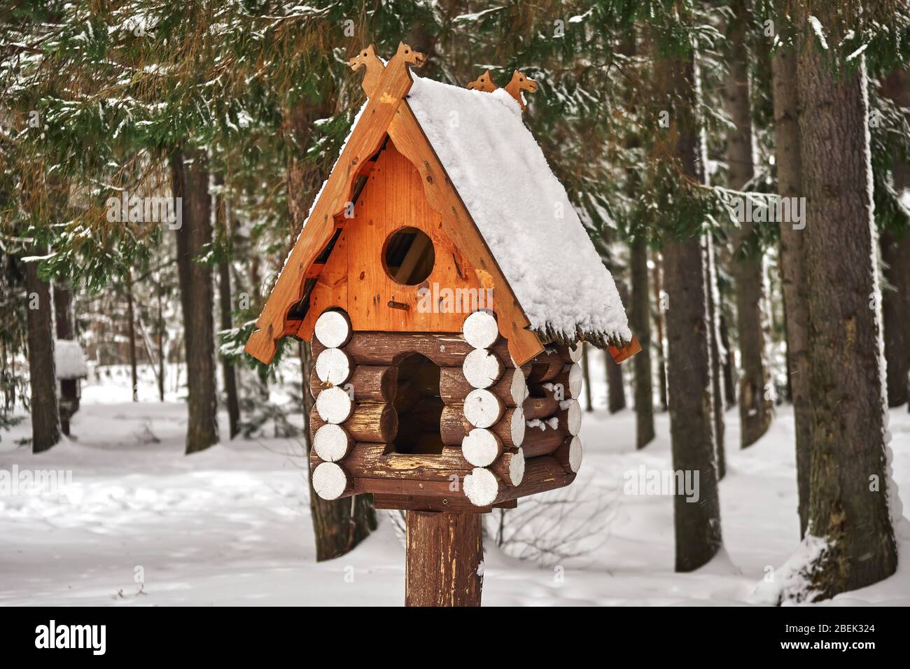 Wooden birdhouse. Handcrafted log cabin birdhouse in snowy forest Stock Photo