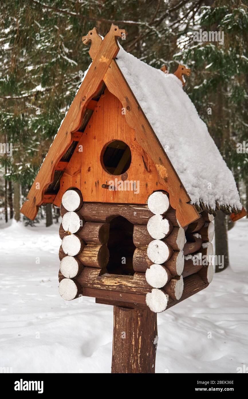 Wooden birdhouse. Handcrafted log cabin birdhouse in snowy forest Stock Photo