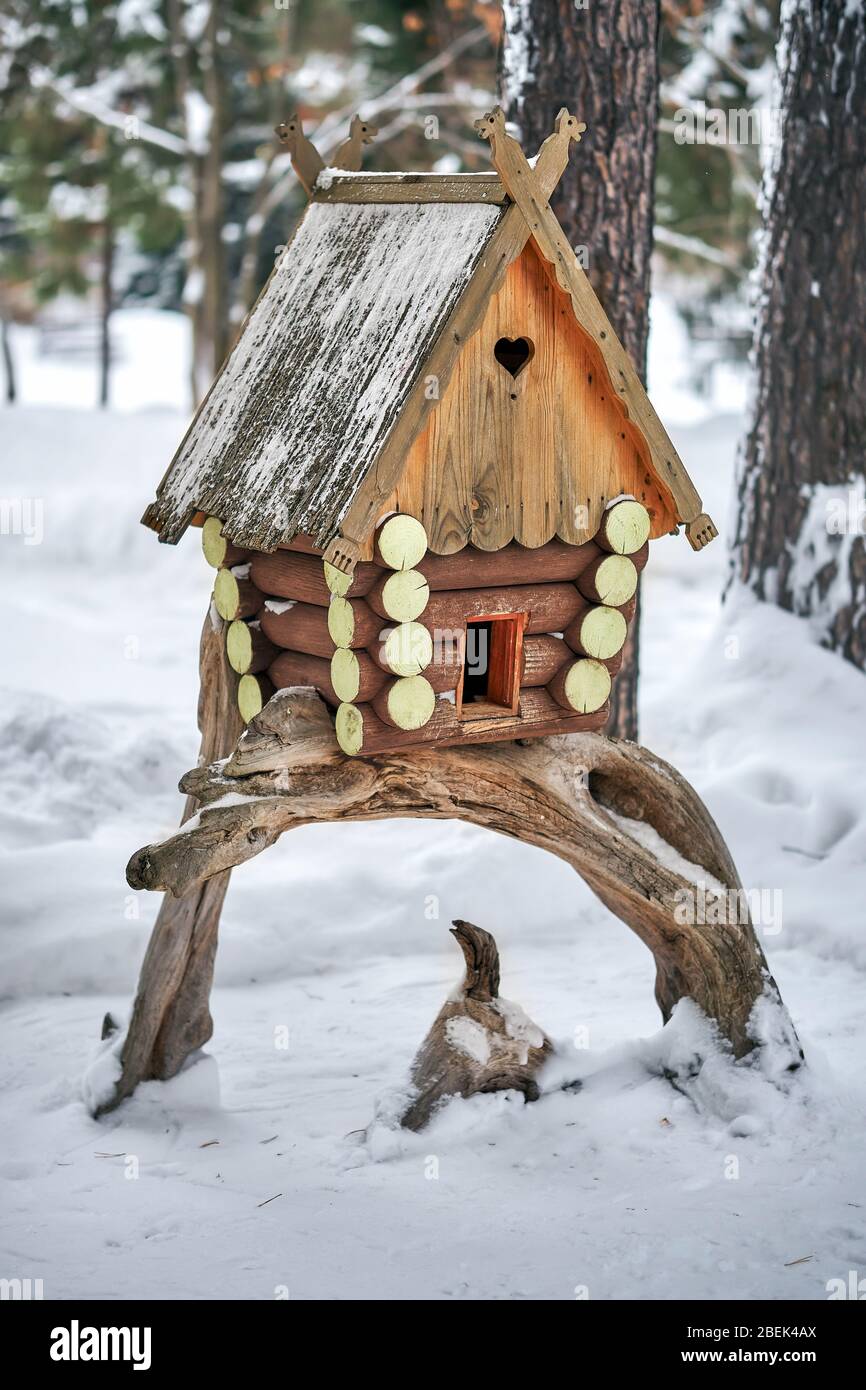 Wooden birdhouse. Handcrafted log cabin birdhouse mounted on snag tree in snowy forest Stock Photo
