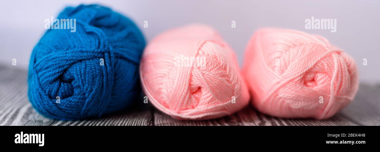 Three colred wool balls laying on the grey wooden background. Banner size. Stock Photo