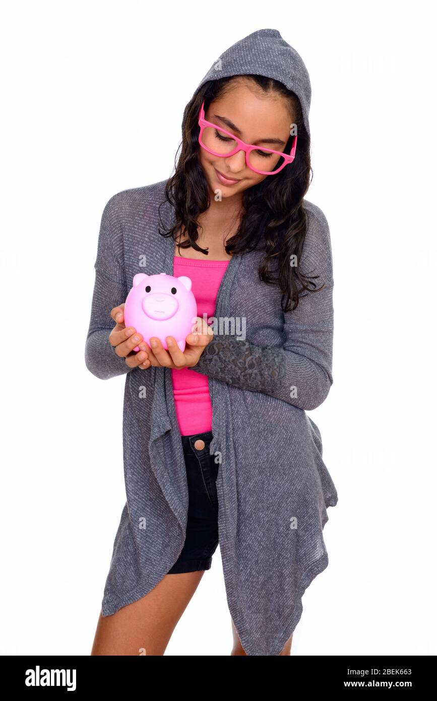 Studio shot of young beautiful teenage girl holding piggy bank isolated ...