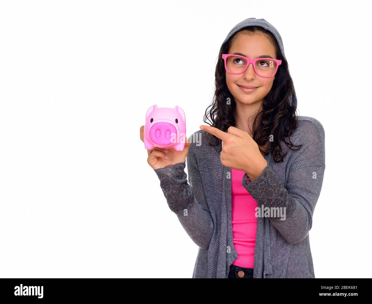 Studio shot of young beautiful teenage girl holding piggy bank and ...