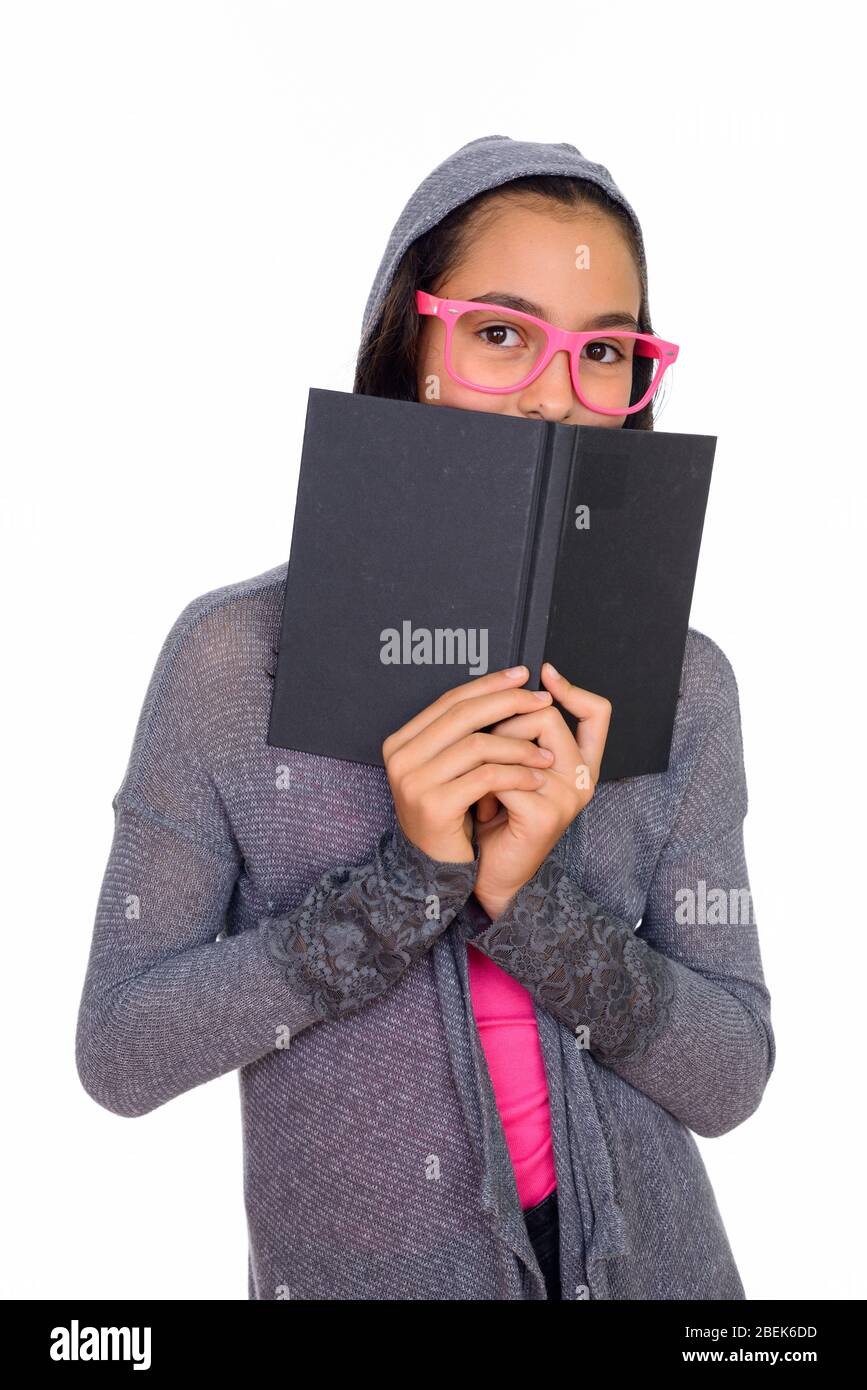 Studio shot of young beautiful teenage girl hiding behind book isolated against white background Stock Photo