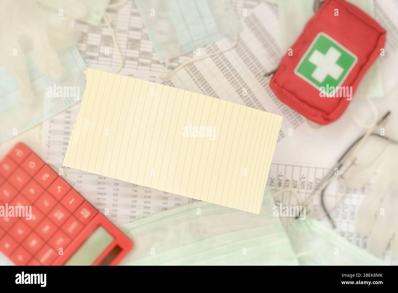 Torn from a notepad sheet in the blurry background of business tables, calculator and personal first aid kit. Remote work concept Stock Photo