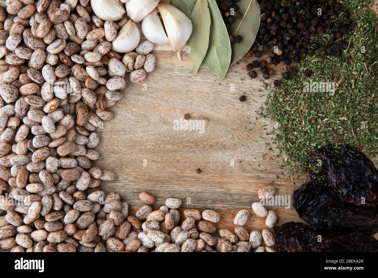 Flat lay of pinto beans, garlic, bay leaves, peppercorns, dried epazote