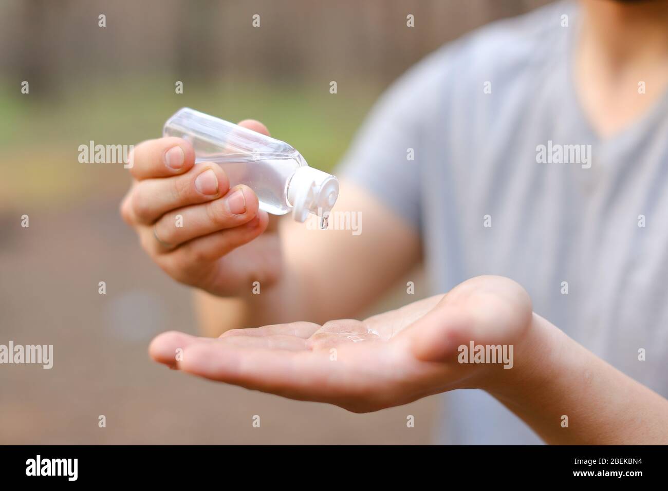 Close up hands using small bottle of alcohol gel sanitizer, to clean or ...